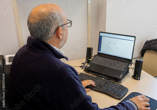 Senior professional man working on a laptop computer in a modern office