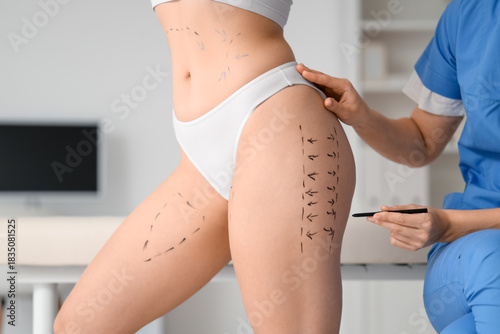 Foto Female plastic surgeon marking patient's thigh in clinic