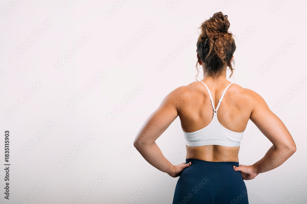Obraz premium Woman showing strong back muscles in workout clothes