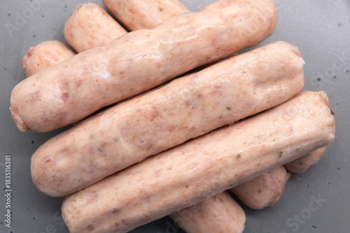 Six uncooked Pork Link Sausages sitting on a plate and ready for cooking.
