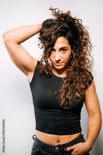 Confident young adult woman with curly hair looking at camera