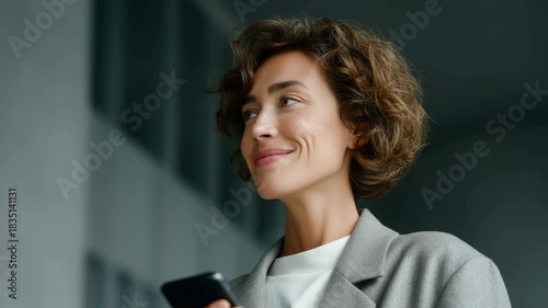 Smiling woman in suit checking phone