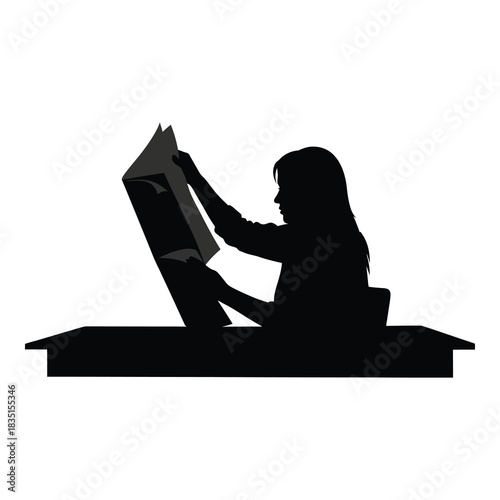 Silhouette of woman absorbed in reading newspaper at desk in quiet moment
