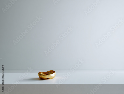 An empty white space with a solitary gold sculpture.