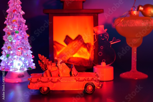 A toy car with Santa on the background of a decorative fireplace and Christmas tree toys.