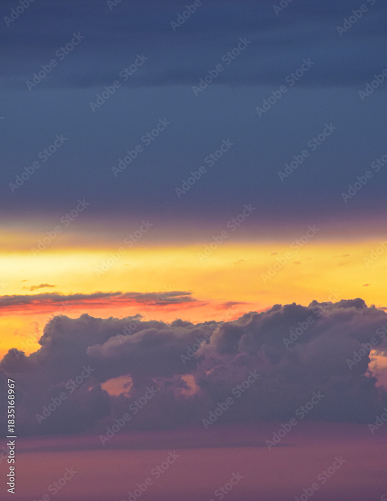 Obraz premium Vibrant sunset sky spreading warm, magical hues across drifting afternoon clouds