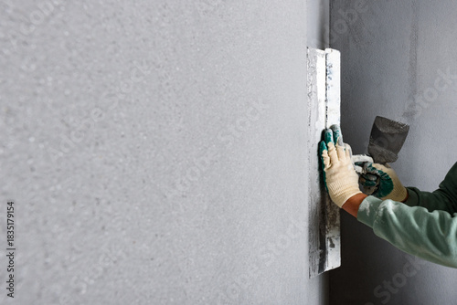 Applying concrete pebble plaster kornik using putty knife.