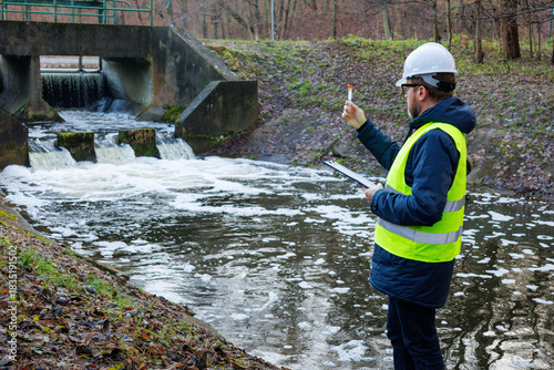 Tablou pe pânză Ecologist taking a water sample near a hydro dam