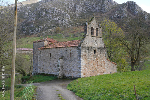 Temple nestles in lush, pine-veiled valley near rural Spain - Rural temple features Arab tiles, bell tower, and surrounding vegetation in La Hermida - Bejes, Cantabria, Spain.