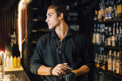 Bartender polishes a glass while standing at the bar