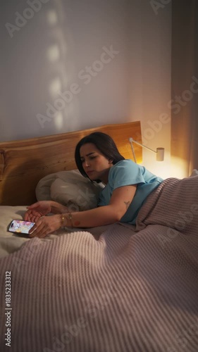 A woman awakens to the sound of a phone notification in her cozy bedroom.