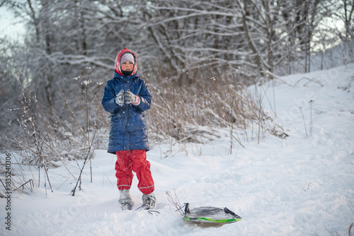 Charming girl with a sled on a snowy winter slope