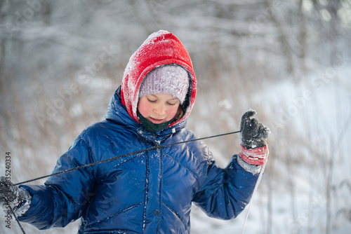Portrait of a charming girl holding a sled rope in snowy winter