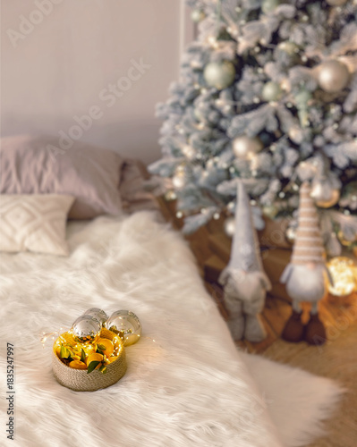 A Christmas tree near the bed. Stylish bedroom interior in nordic style. Christmas tree at home.