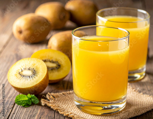 A glass of golden kiwi fruit juice on a wooden background