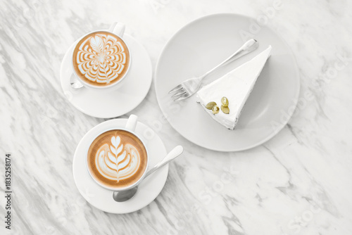 Two cups of coffee with cake art on white background
