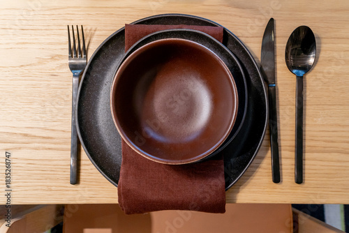 Table setting with plate, knife, spoon, fork and napkin on a informal dining indoor