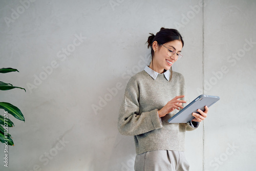 Photography Smiling young woman wearing casual business attire and glasses, reading or typin