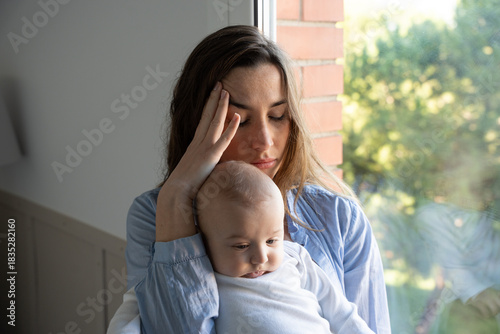 Foto Exhausted mother caring for her newborn while facing postpartum depression