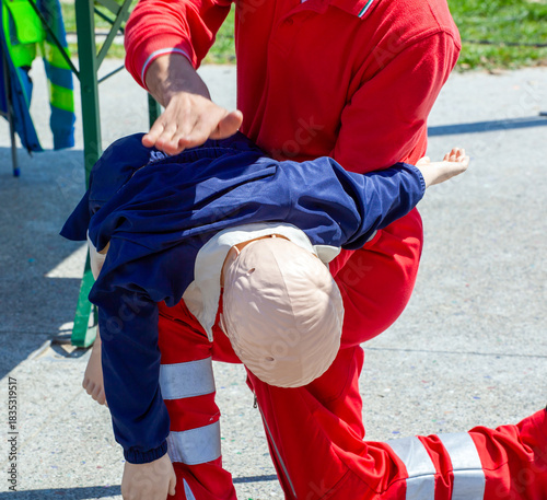 First aid instructor performing back blows on child dummy