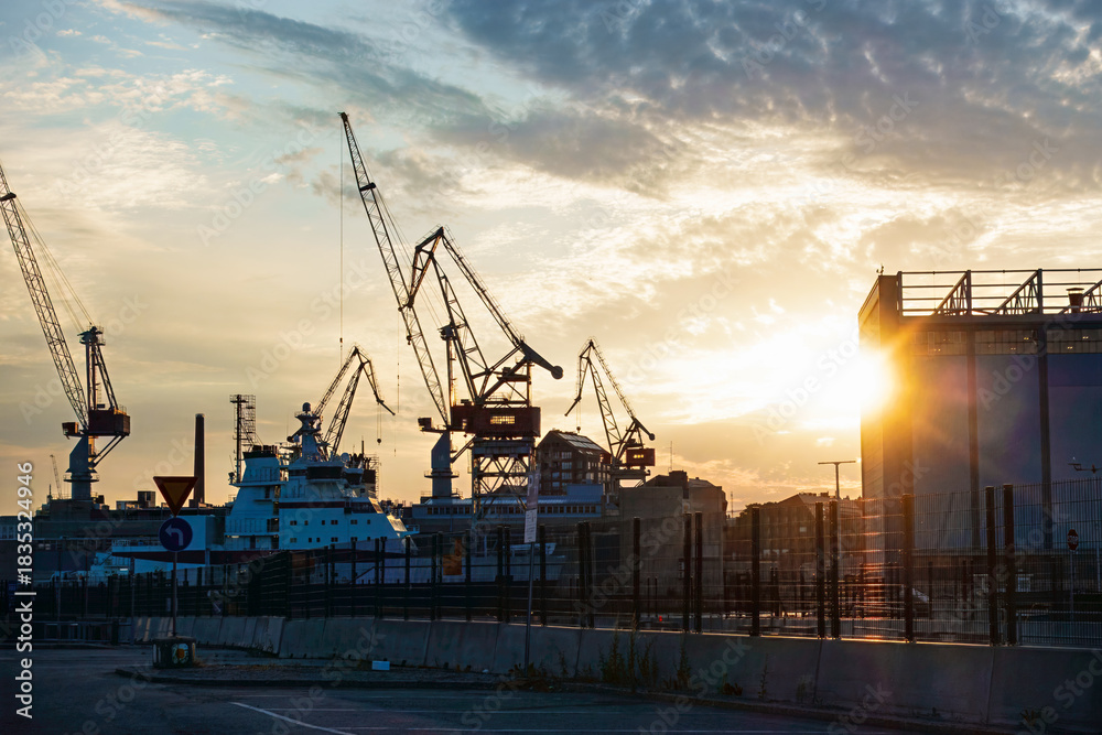 Fototapeta premium Industrial port at sunset with shipyard cranes and ship