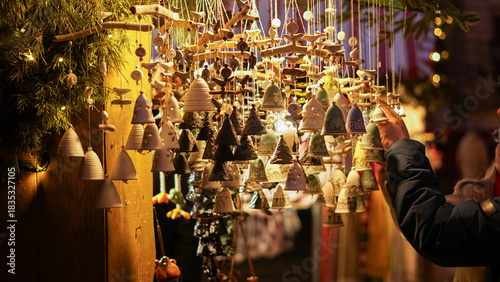 A cozy display of handmade ceramic bells with intricate blue patterns hangs in warm light at a Christmas market. Perfect for festive decor, crafts, and gift inspiration this season ahead.