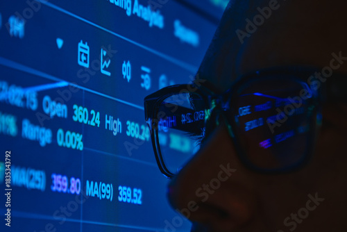 Trader's eye viewing stock market statistics and financial data reflecting in glasses