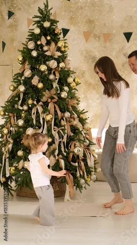 a happy family at the Christmas tree at home waiting for the new year, enjoying and hugging each other, having fun together, the new year at home