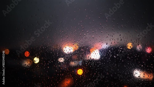 窓の雨粒と遠くの街灯のボケ、雨の夜に広がる感傷的な都会の夜景背景