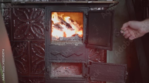 Opening and closing the door of a wood burning stove during evening use in a cozy room