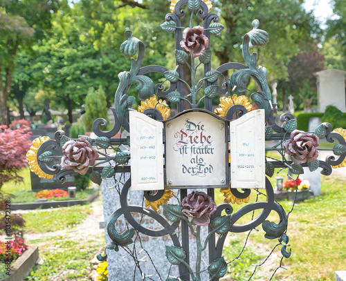 Wunderschönes Blumenverziertes Eisenkreuz mit einem Frommen Wunsch auf dem Katholischen Friedhof in Kempten - Allgäu