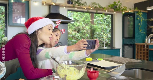 After taking phone selfies mother and Indian daughter mixing batter at counter for holiday baking