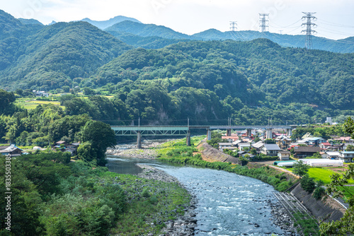 群馬県利根川とJR上越線鉄橋、夏の山々に囲まれた集落の風景