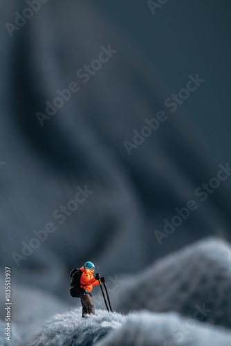 A miniature mountain climber figurine on a fuzzy fleece lining resembling a snow-covered surface, with a blurred background of a mountain or ice wall