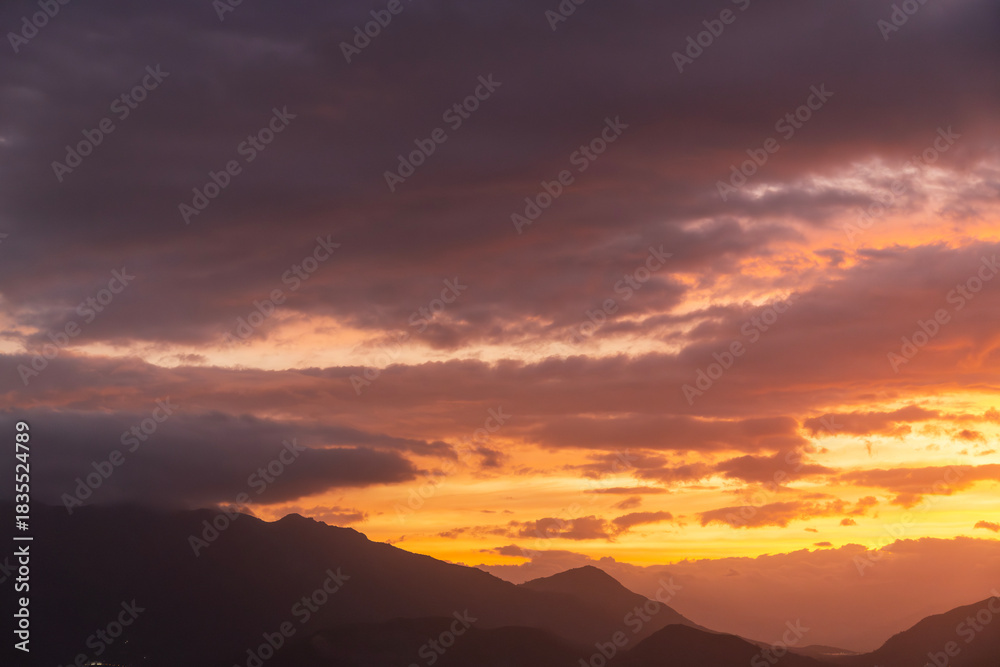 Obraz premium Bright sunset over the silhouette mountains at evening time.