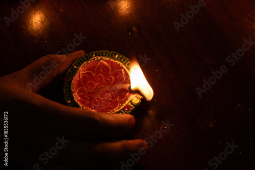 Hand grabs the colorful oil lamp to prepare for Karthigai deepam celebration in Tamil Nadu