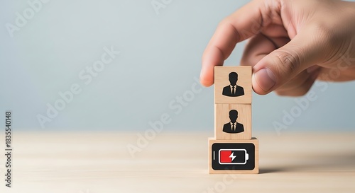 Hand placing wooden block with employee icon on top of other blocks, representing employee burnout and low energy level