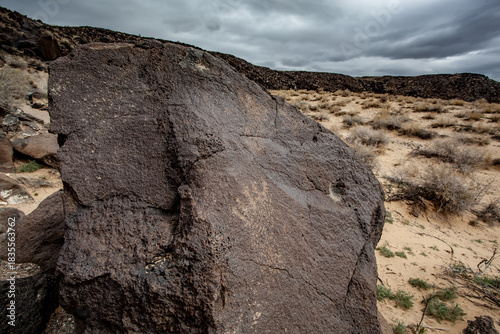 Weathered petroglyph etched into volcanic rock at Petroglyph National Monument in New Mexico's desert landscape.
