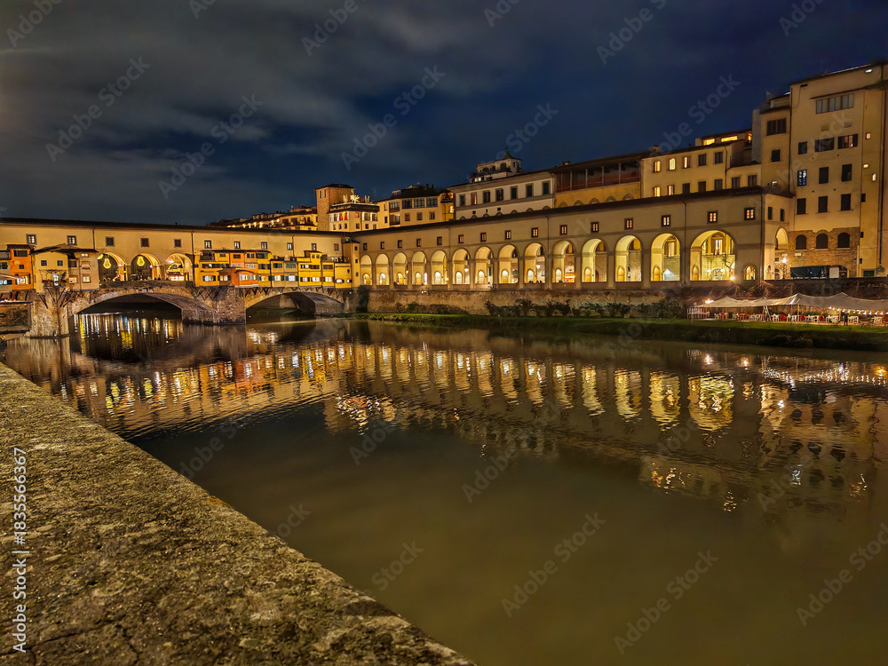 Obraz premium View of Ponte Vecchio in Florence, a medieval stone bridge lined with charming jewelry shops, offering stunning views of the Arno River and a lively atmosphere that captures the city’s historic charm