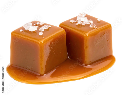 Two glistening salted caramel cubes with sea salt flakes and a puddle of caramel on a transparent background