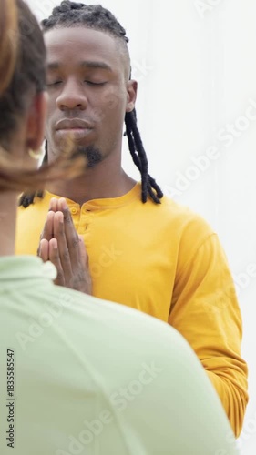 Vertical video: Entering frame, man in yellow shirt meditating on balcony, with fabric canopy