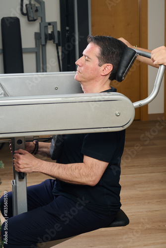 Man strengthening neck muscles using therapy machine