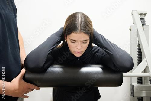 Young woman training back muscles with personal trainer