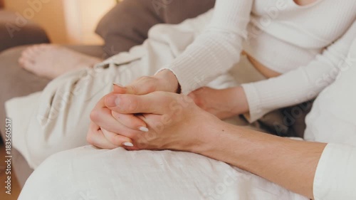 Close up Couple sitting on a couch holding hands during a quiet moment in an indoor space, sharing warmth and connection in the afternoon light