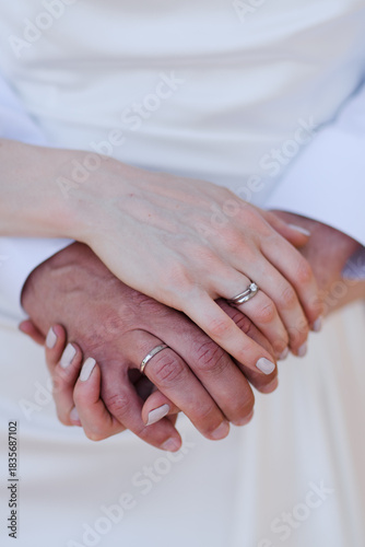 Caucasian bride and a groom holding hands, wearing wedding rings on their fingers. Just married couple close-up.