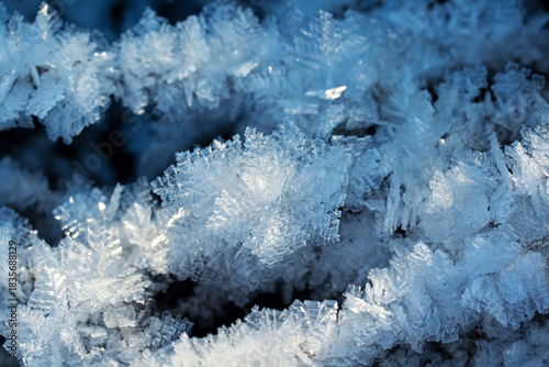 Holiday background with shiny crystals of cold blue transparent snowflakes an...