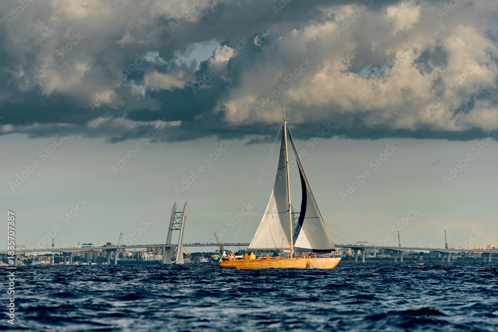 Obraz premium The lonely old wooden sailboat at sunny day, bridge on background, sailing regatta in the Gulf of Finland, sailing yacht competing in a race, splashing water, board the boat