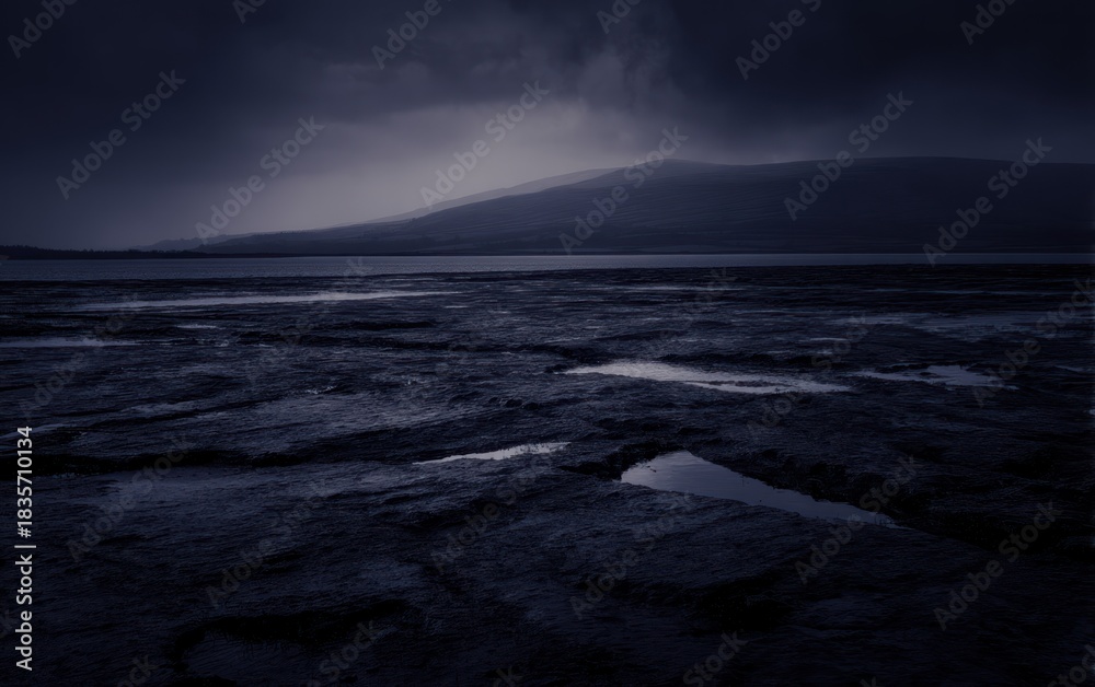 Fototapeta premium Dramatic landscape view with water and mountains under a cloudy overcast sky
