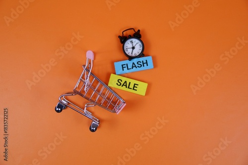 Photos A miniature shopping cart sits on a orange backdrop beside a small clock and colorful signs reading 'Flash' and 'Sale', conveying urgency, discounts, and quick shopping ideas