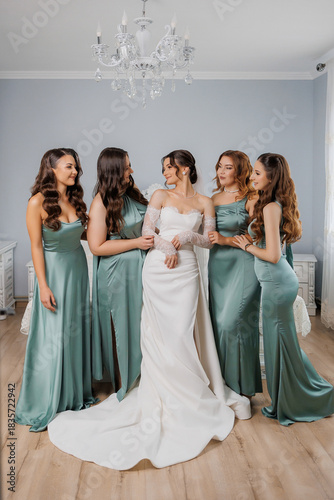 Bridesmaids gather with the bride for final moments before wedding ceremony in bright room